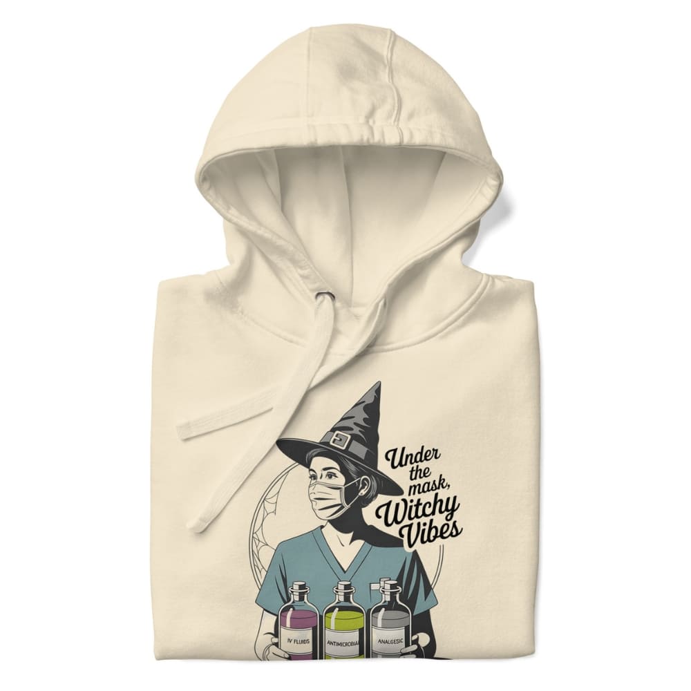 Beige hoodie with a graphic of a witch wearing a mask and text 'Under the mask, Witchy Vibes' on a white background.