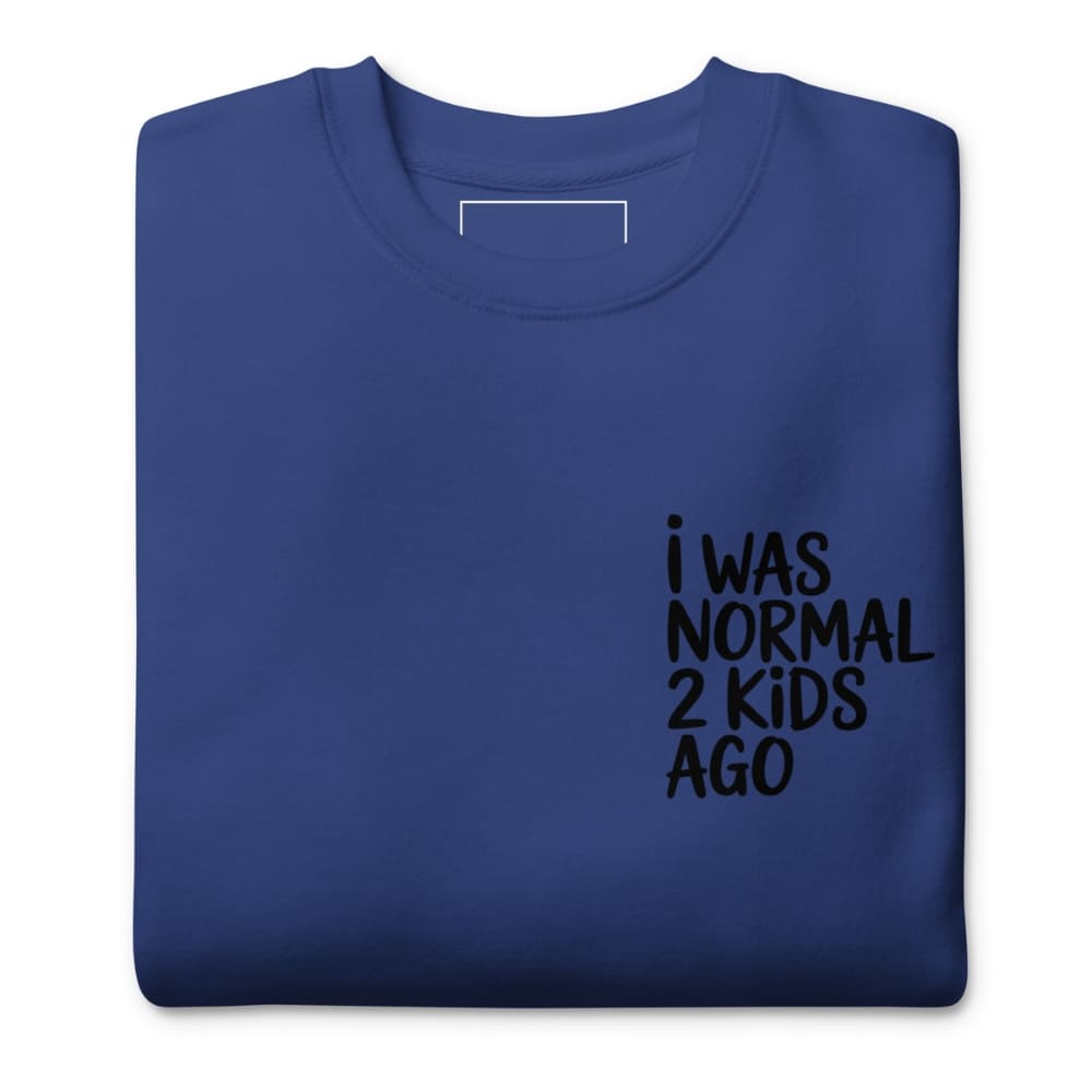 Folded blue sweatshirt with black text 'I WAS NORMAL 2 KIDS AGO' on a white background