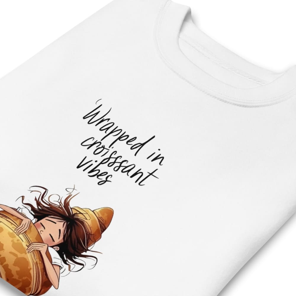 White t-shirt with a cartoon character in a croissant and text 'Wrapped in croissant vibes' on a white background