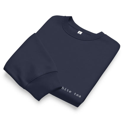 Folded navy blue sweatshirt with 'hite tea' text on a white background