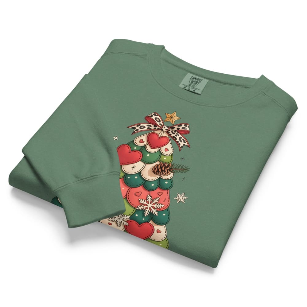 Folded green sweatshirt with Christmas tree design on a white background