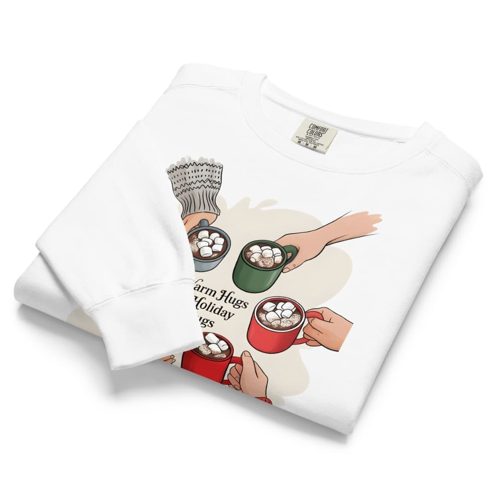 Folded white sweatshirt with graphic design of hands holding mugs of hot chocolate and marshmallows on a white background.