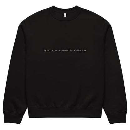 Black sweatshirt with text 'Hazel eyes steeped in white tea' on a white background
