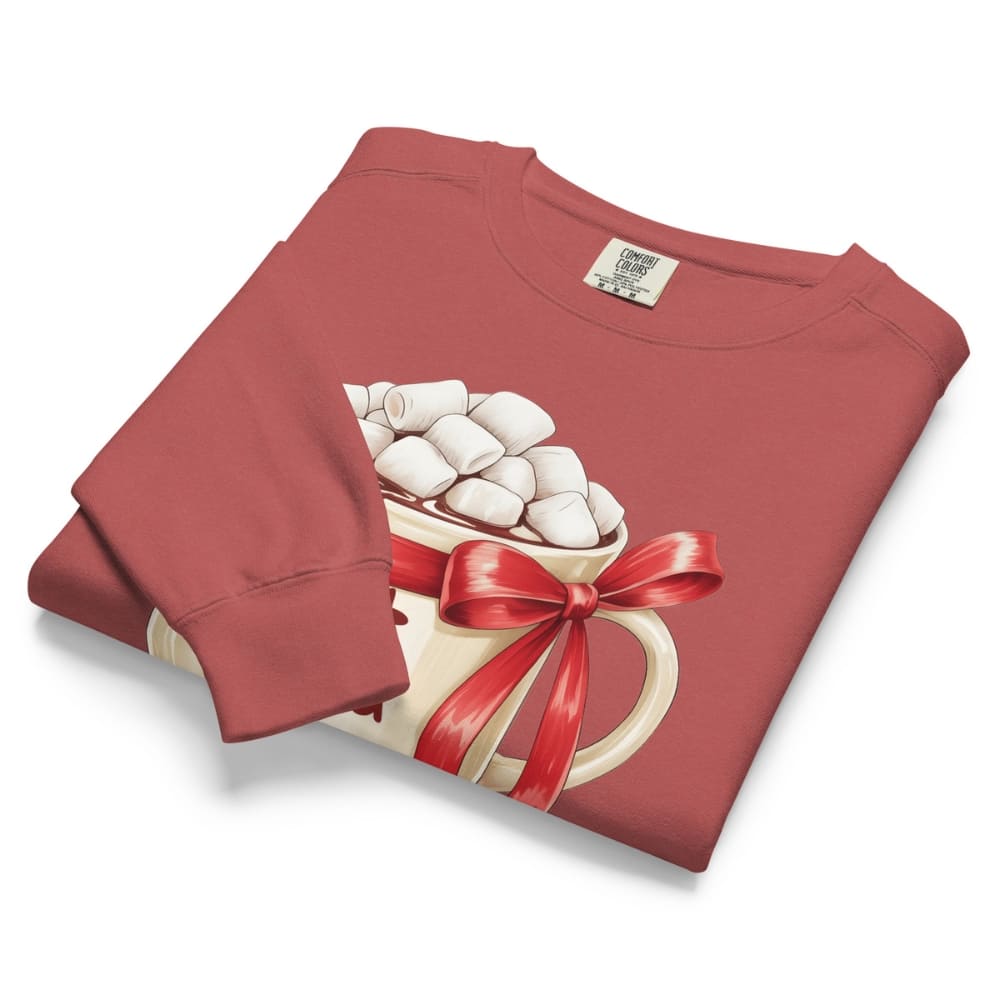 Folded red sweatshirt with a graphic of a mug of hot chocolate and marshmallows, tied with a red ribbon.