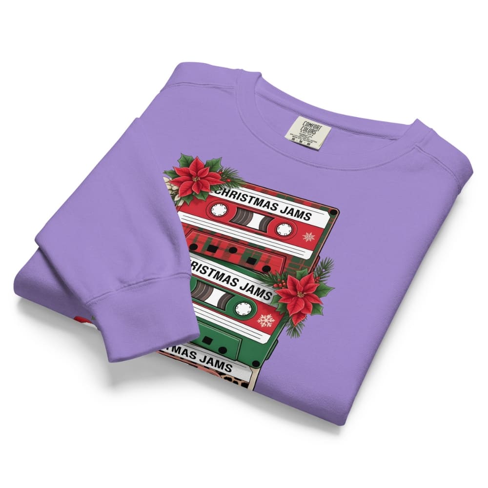 Folded purple sweatshirt with Christmas-themed cassette tape design on a white background