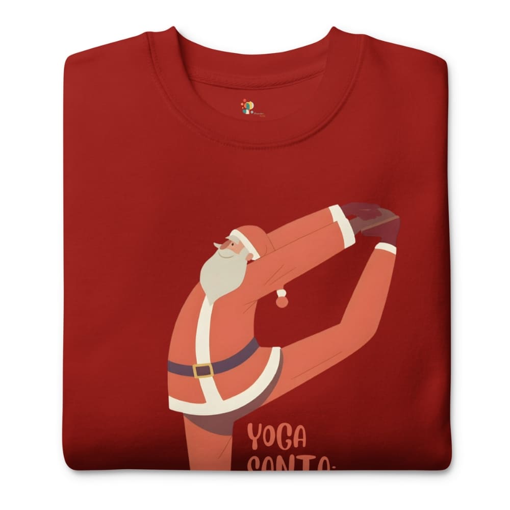 Folded red t-shirt with a graphic of Santa Claus doing yoga on a white background