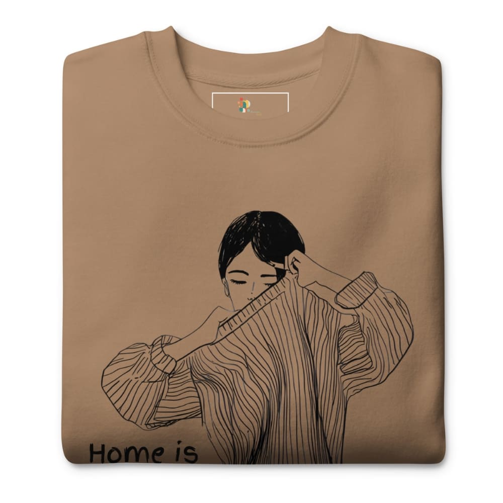 Folded brown sweatshirt with a black and white illustration of a person wearing a sweater and text 'Home is'