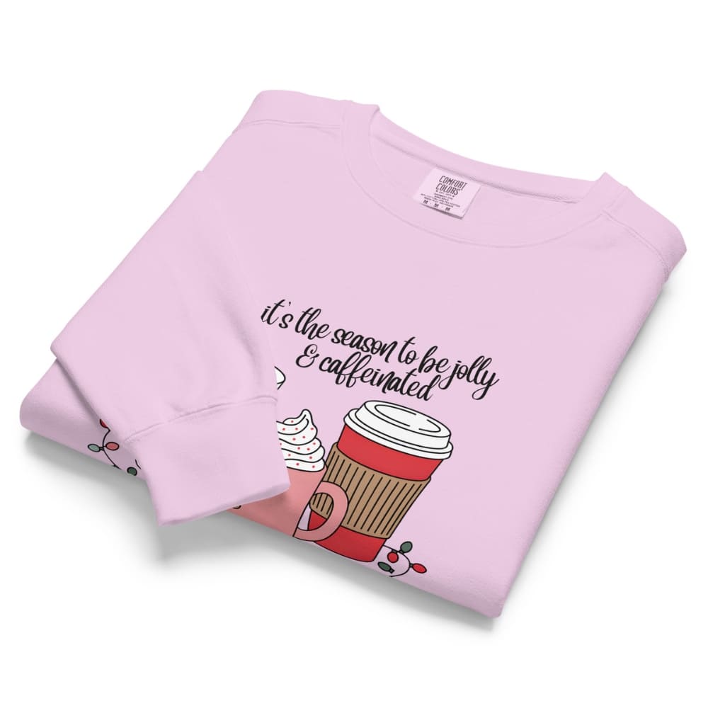 Folded pink sweatshirt with coffee cup graphic and text on a white background