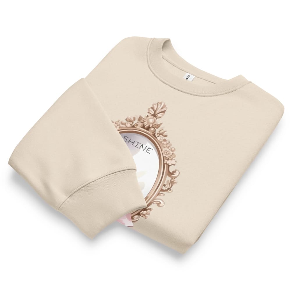 Beige sweatshirt with decorative emblem and 'SHINE' text on a white background