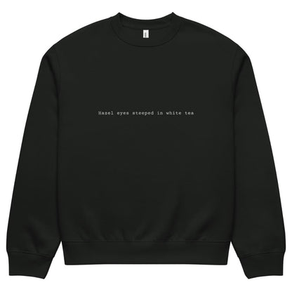 Black sweatshirt with text 'Hazel eyes steeped in white tea' on a white background