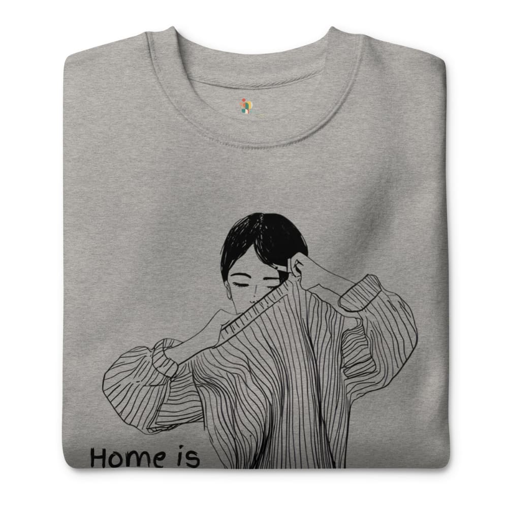 Gray sweatshirt with a black and white illustration of a person wearing a sweater, with 'Home is' text at the bottom.