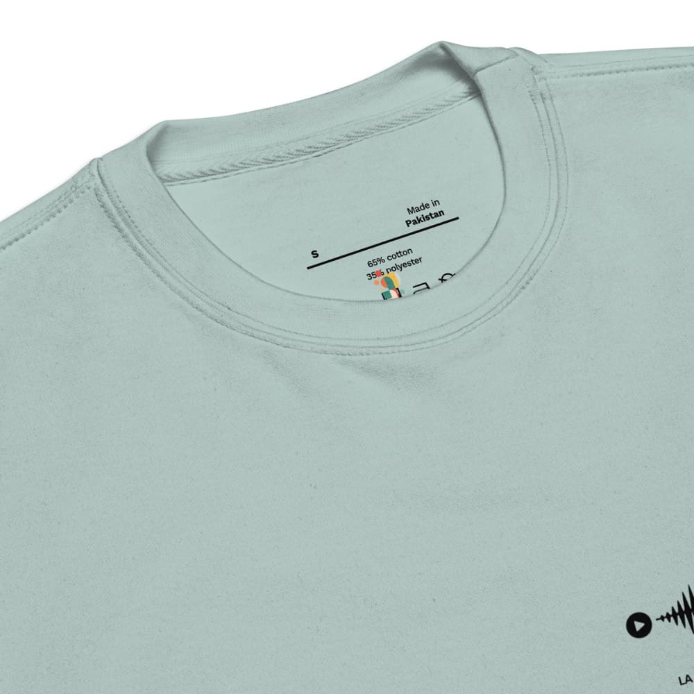 Light blue t-shirt with a label on the collar showing 'Made in Pakistan' and fabric composition.
