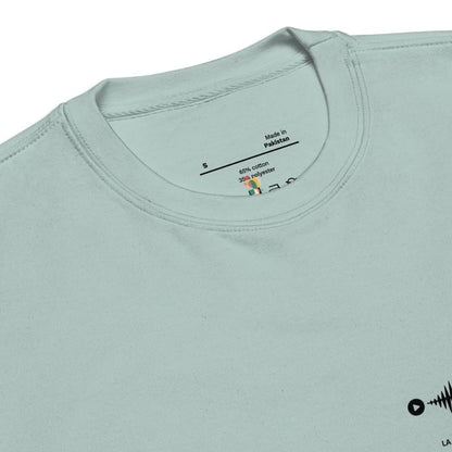 Light blue t-shirt with a label on the collar showing 'Made in Pakistan' and fabric composition.