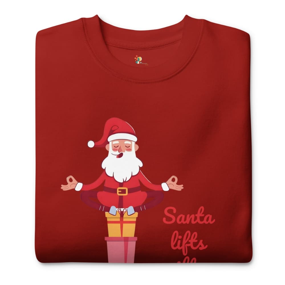 Folded red t-shirt with a cartoon Santa Claus meditating on a present, text 'Santa lifts' on a white background.