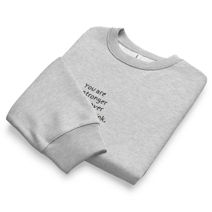 Folded gray sweatshirt with motivational text on a white background