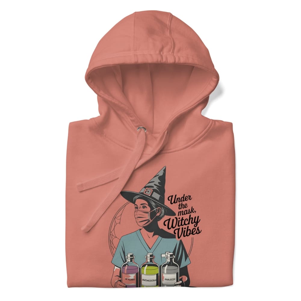 Pink hoodie with a graphic design of a person wearing a witch hat and potion bottles, with text 'Under the mask, Witchy Vibes'.