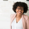 Woman wearing glasses and a pink blazer against a white background