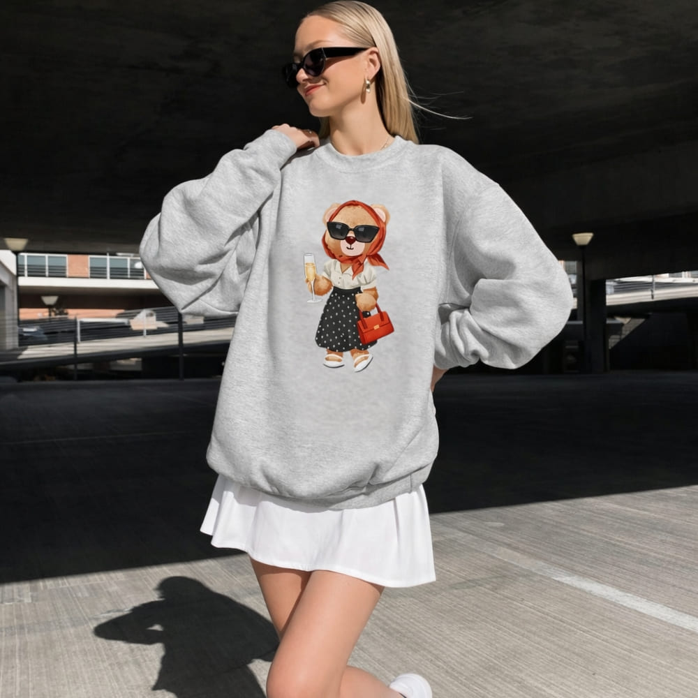 Woman wearing a gray sweatshirt with a teddy bear design outdoors.