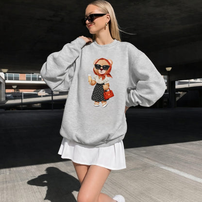 Woman wearing a gray sweatshirt with a teddy bear design outdoors.