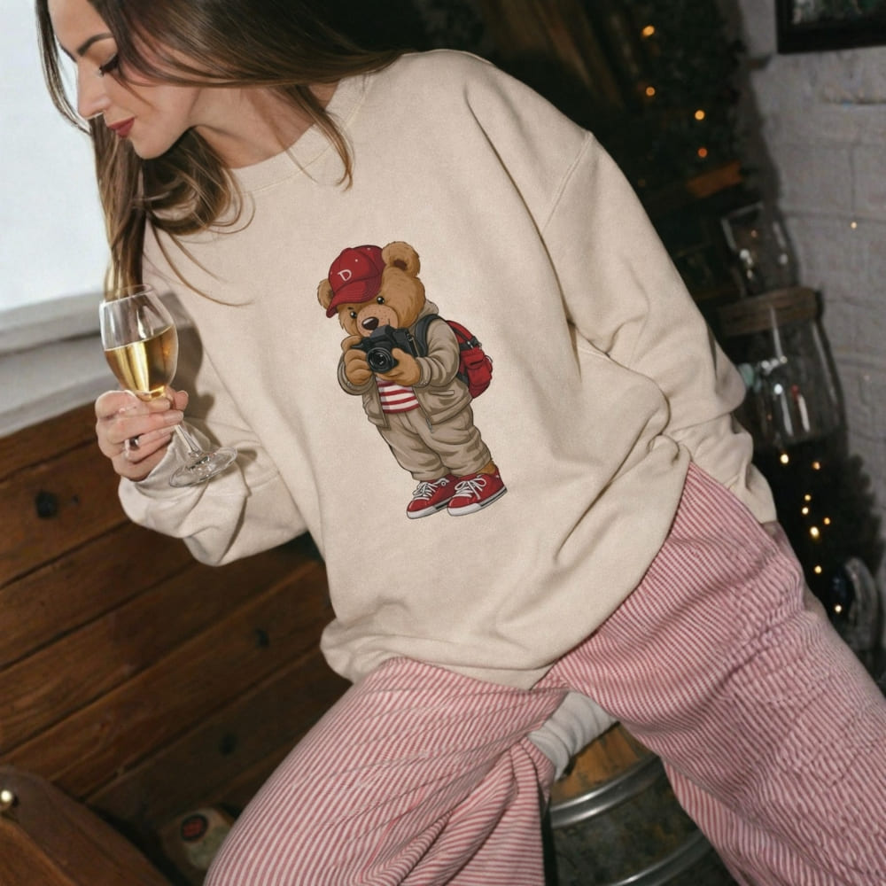 Person wearing a sweatshirt with a bear graphic, holding a glass of champagne.