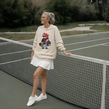 Woman in a beige sweatshirt with a graphic design, white skirt, and white sneakers standing on a tennis court.
