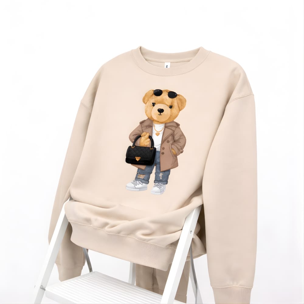 Beige sweatshirt with a teddy bear graphic on a white background