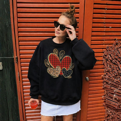 Woman wearing a black sweatshirt with a heart design, standing in front of a red door.