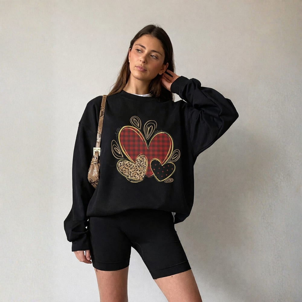 Woman wearing a black sweatshirt with heart design against a plain background