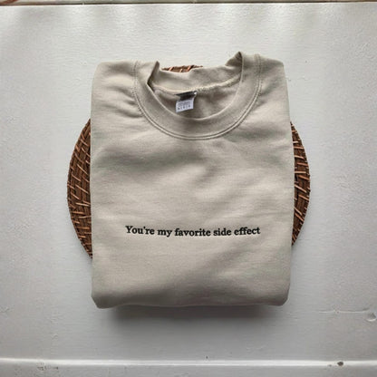 Folded beige sweatshirt with text on a light gray background