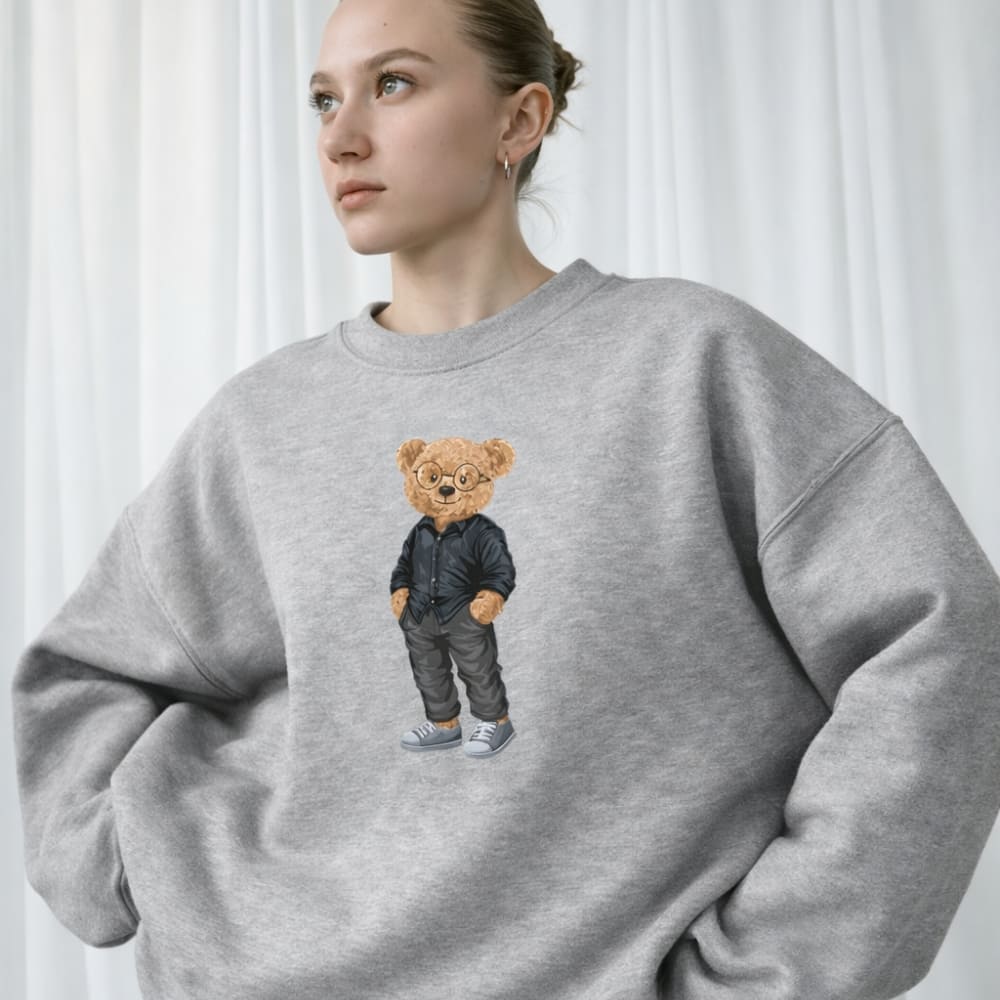Person wearing a gray sweatshirt with a teddy bear graphic on a white background