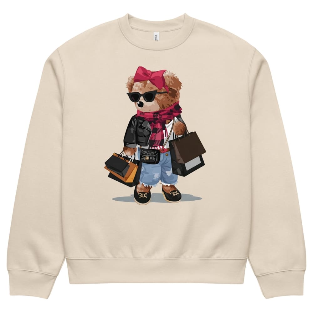Beige sweatshirt with a teddy bear graphic wearing sunglasses, a pink bow, and holding bags on a white background.
