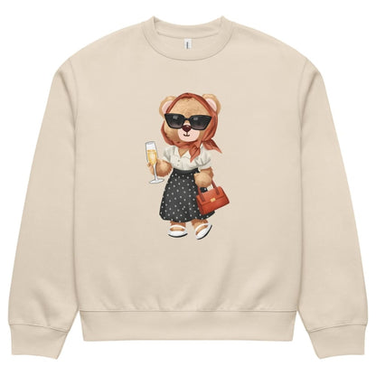 Beige sweatshirt with a teddy bear design holding a glass of champagne and a handbag on a white background