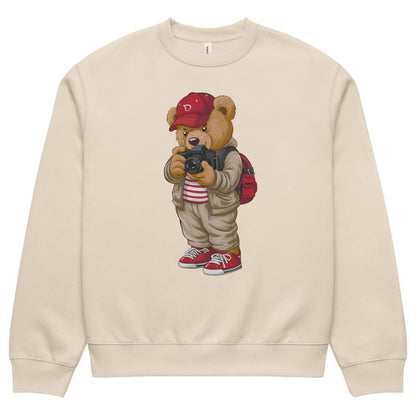 Beige sweatshirt with a cartoon bear wearing a red cap and backpack holding a camera on a white background