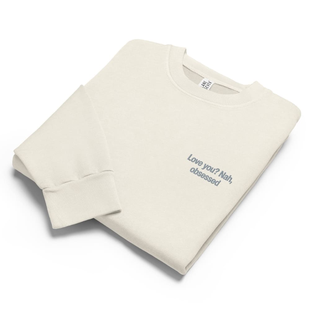 Folded beige sweatshirt with text on a white background