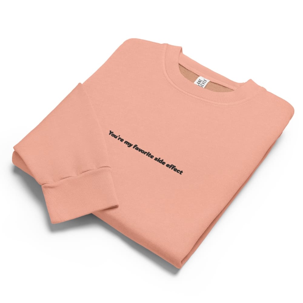 Folded pink sweatshirt with text on a white background