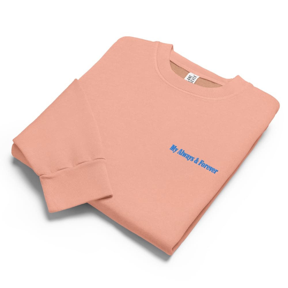Folded peach-colored sweatshirt with blue text on a white background