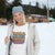 Person wearing a white sweatshirt with colorful text in a snowy outdoor setting