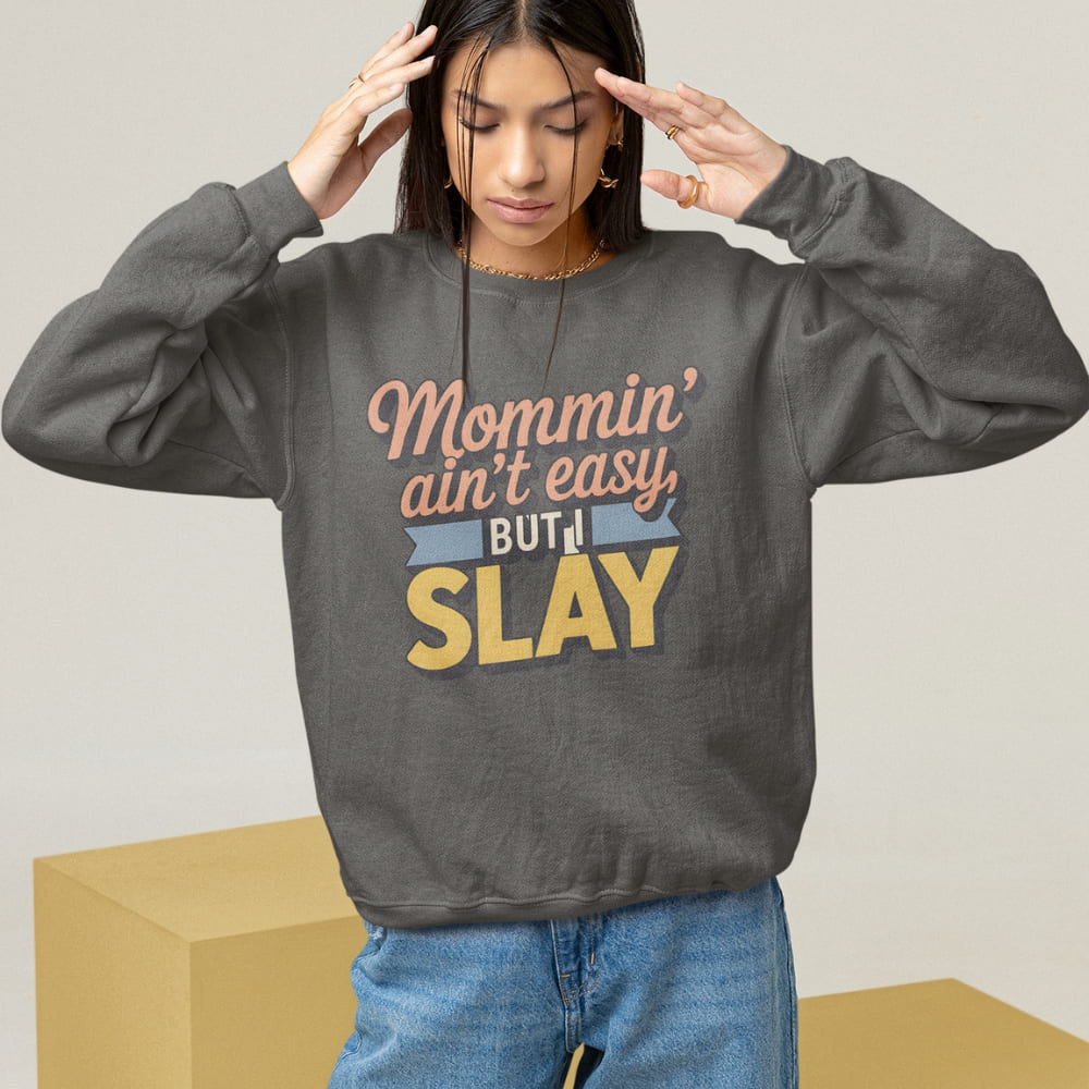 “Mommin' Ain’t Easy But I Slay” retro-style DTG printed design in peach, blue, and yellow on vintage garment-dyed fleece sweatshirt