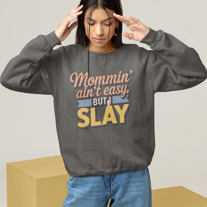 “Mommin' Ain’t Easy But I Slay” retro-style DTG printed design in peach, blue, and yellow on vintage garment-dyed fleece sweatshirt