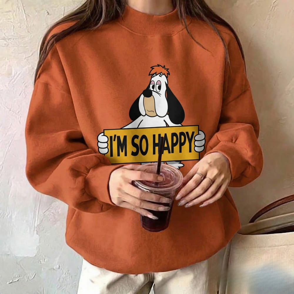 Person wearing an orange sweatshirt with a cartoon character and 'I'm so happy' text, holding a drink.
