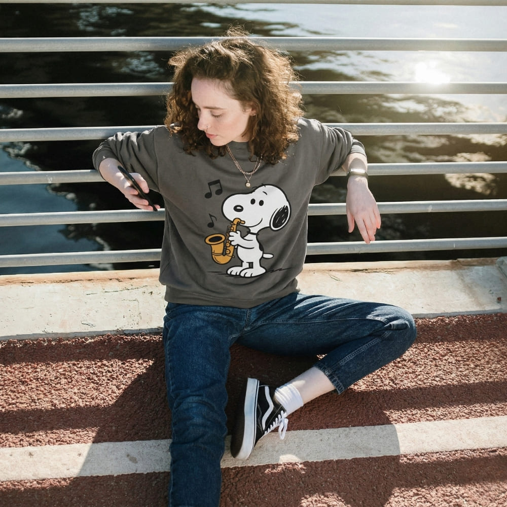 Person wearing a gray sweatshirt with a cartoon character sitting on a bench.