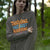 Person wearing a gray sweatshirt with 'THRIVING, NOT JUST SurvIVING' text in a forest setting