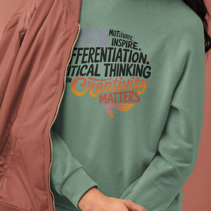 Green sweatshirt with motivational text worn by a person, against a pink background