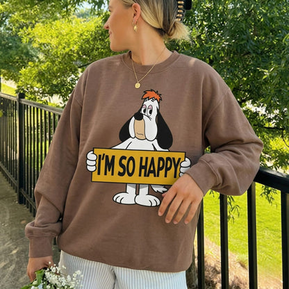Person wearing a brown sweatshirt with a cartoon character holding 'I'm So Happy' sign outdoors.