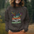 Person wearing a dark gray sweatshirt with colorful text and graphics outdoors.