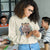 Woman wearing a 'Nurse Squad' sweatshirt using a phone in an office setting