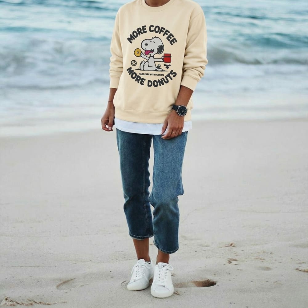 Person wearing a beige sweatshirt with a graphic design on a beach