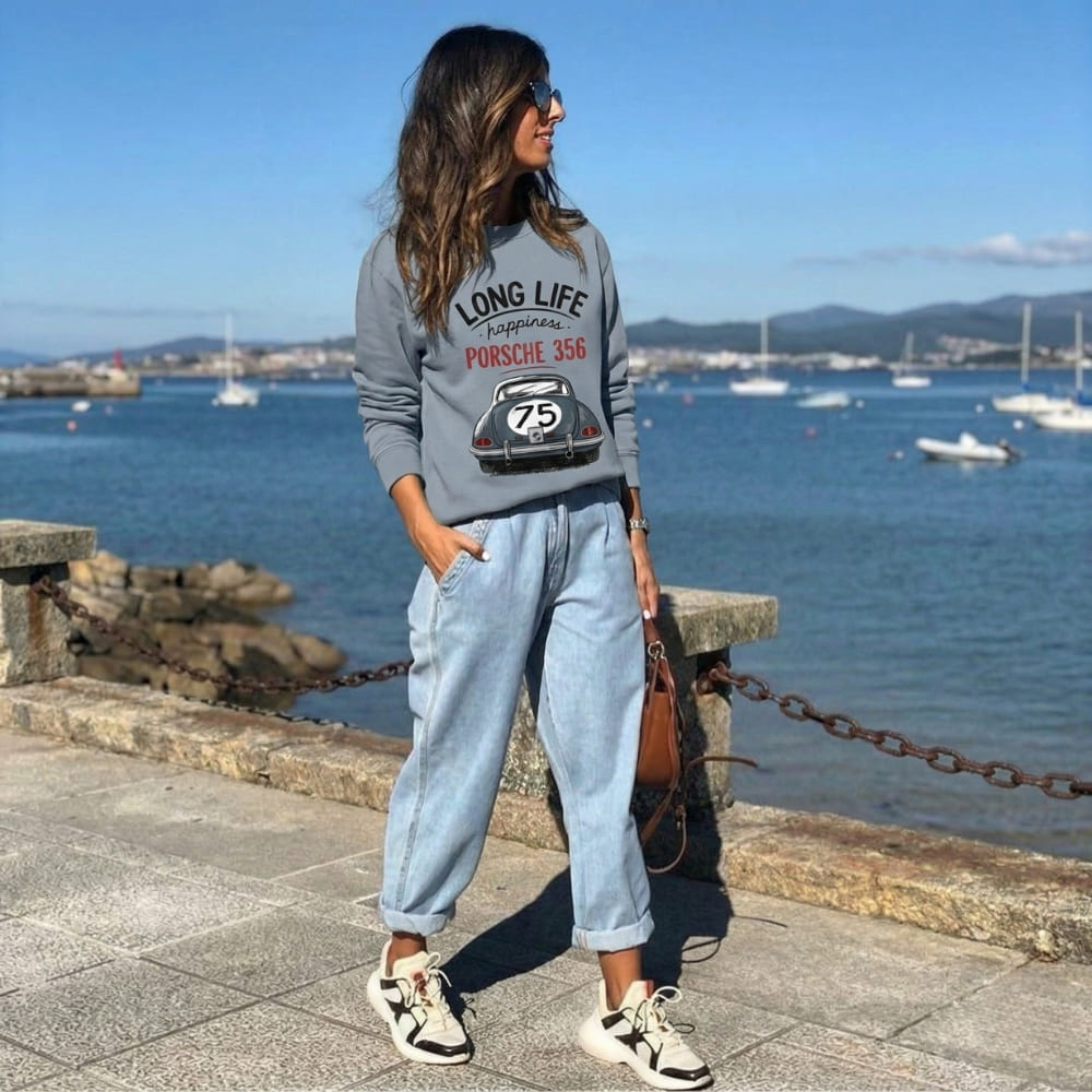 Woman wearing a blue sweatshirt with a Porsche design by the waterfront