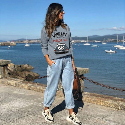 Woman wearing a blue sweatshirt with a Porsche design by the waterfront