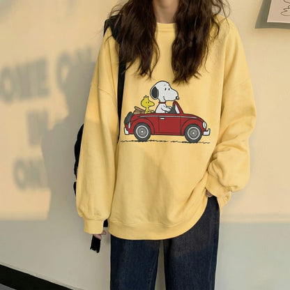 Person wearing a yellow sweatshirt with a cartoon design of Snoopy and Woodstock in a car.